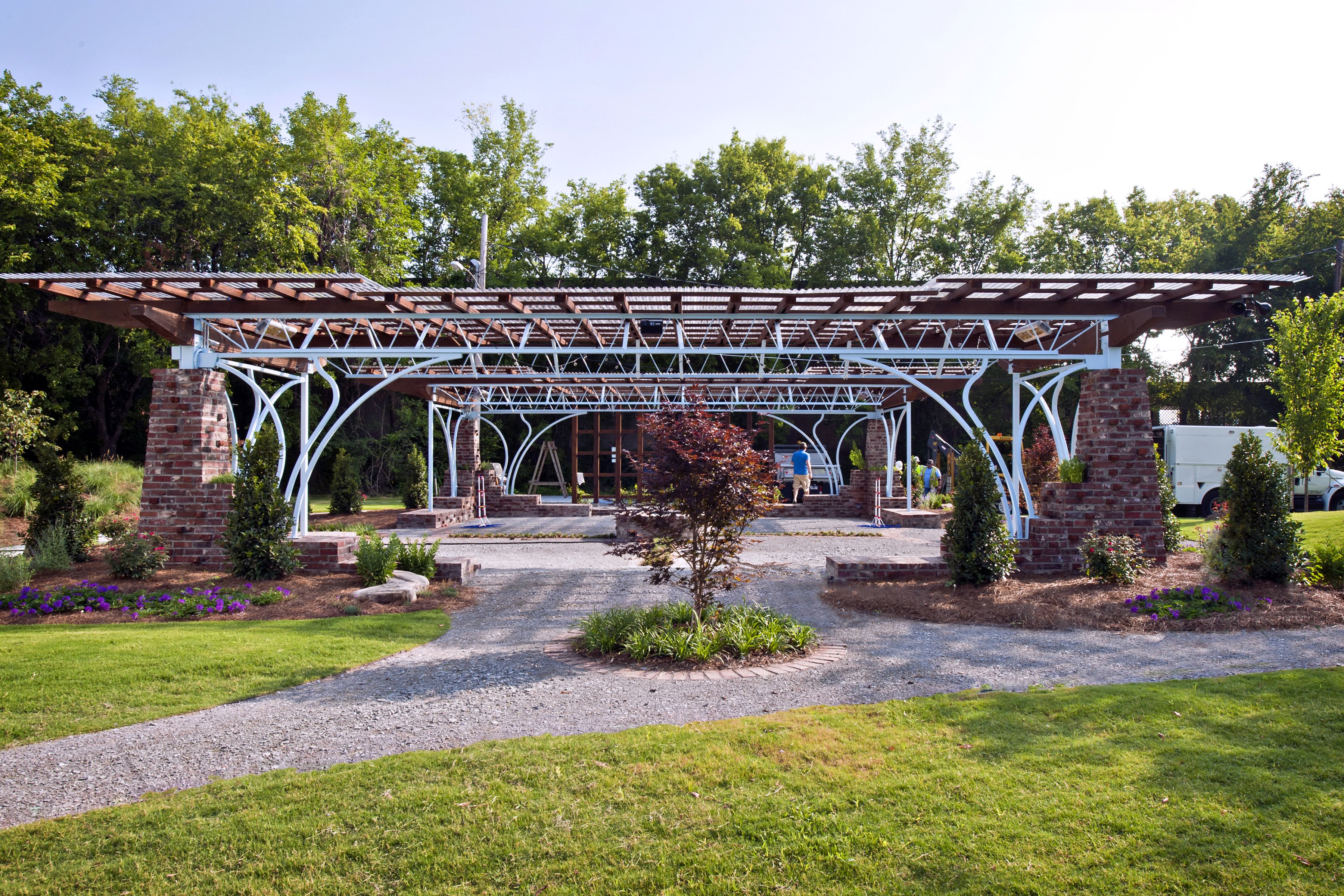 A covered outdoor area with a brick structure, gravel path, and greenery.
