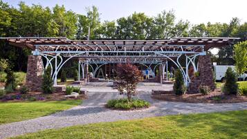 A covered outdoor area with a brick structure, gravel path, and greenery.