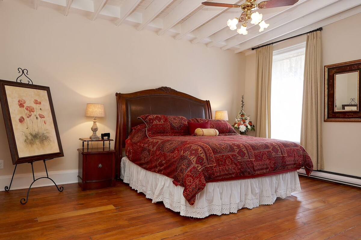 A bedroom with a wooden bed, two bedside tables, a ceiling fan, and a large mirror.