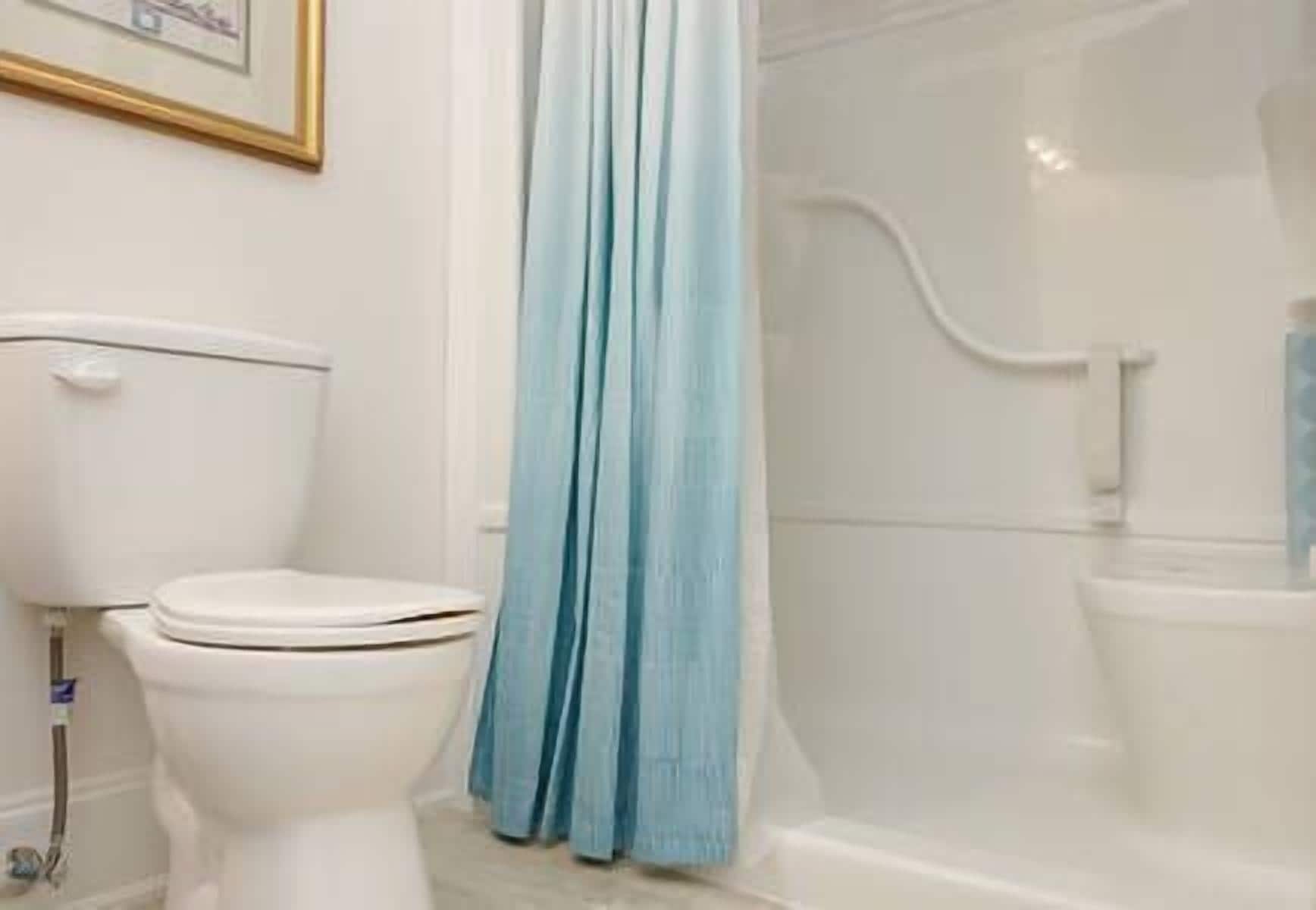 Un baño con inodoro, ducha y cortina.