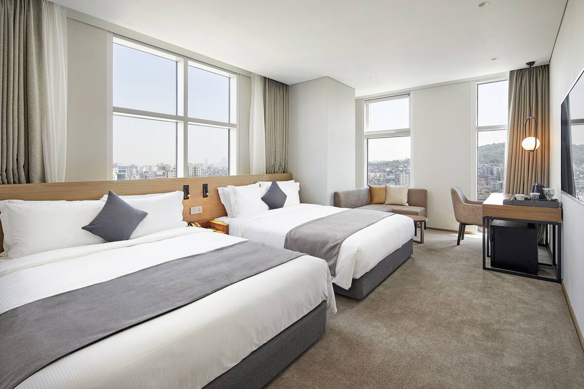 Een hotelkamer met twee bedden, een bureau en een stoel.