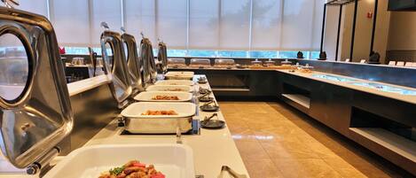 A buffet setup with multiple serving stations, a variety of food items, and a modern interior design.