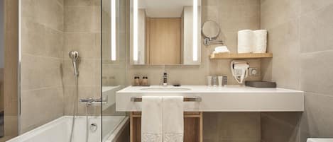 Un baño moderno con ducha envuelta en vidrio, tocador con espejo y un inodoro.