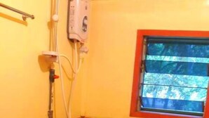 Une salle de bain équipée de toilettes, d’une fenêtre et d’un distributeur de gel hydroalcoolique.