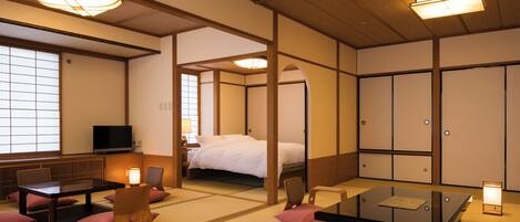 A traditional Japanese room with tatami flooring, a low table, a bed, and sliding doors.