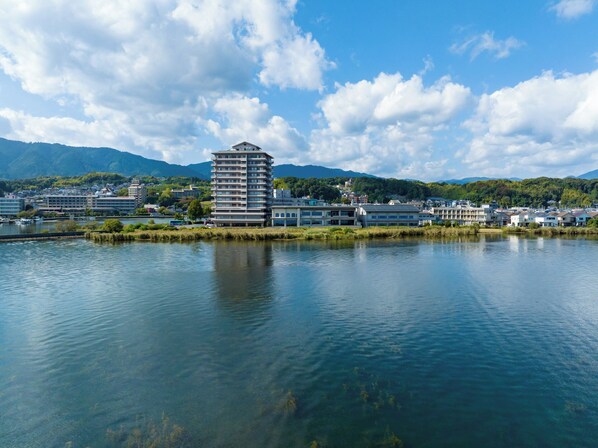 Un hôtel situé au bord de l’eau, doté d’un bâtiment moderne à plusieurs étages, d’un port de plaisance et offrant une vue imprenable sur les montagnes et la verdure.