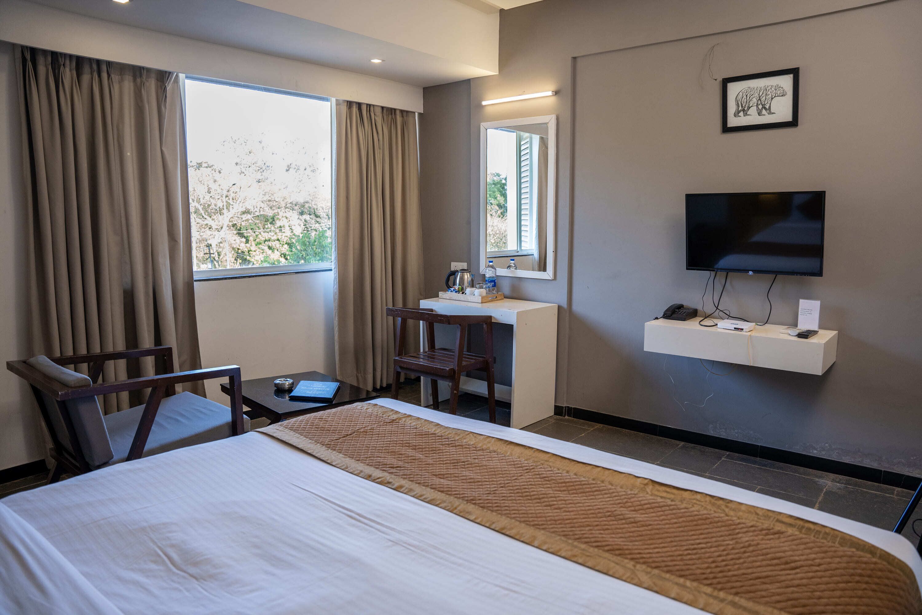 Een hotelkamer met een bed, een bureau, een stoel, een televisie en een raam met gordijnen.