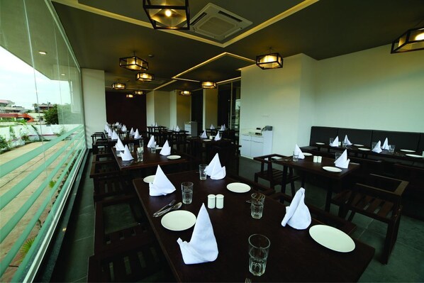 A restaurant with multiple tables set for dining, featuring white napkins, plates, and cutlery. - Dwarawata Dharwad (Dharwad)