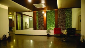 A spacious lobby with a modern design, featuring a red chair, potted plants, and a large mirror wall. - Dwarawata Dharwad (Dharwad)