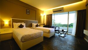 A hotel room with two beds, a small table, and a view of greenery outside. - Dwarawata Dharwad (Dharwad)