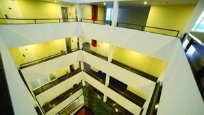 A multi-level interior with a central atrium, glass railings, and a red door on the upper level. - Dwarawata Dharwad (Dharwad)