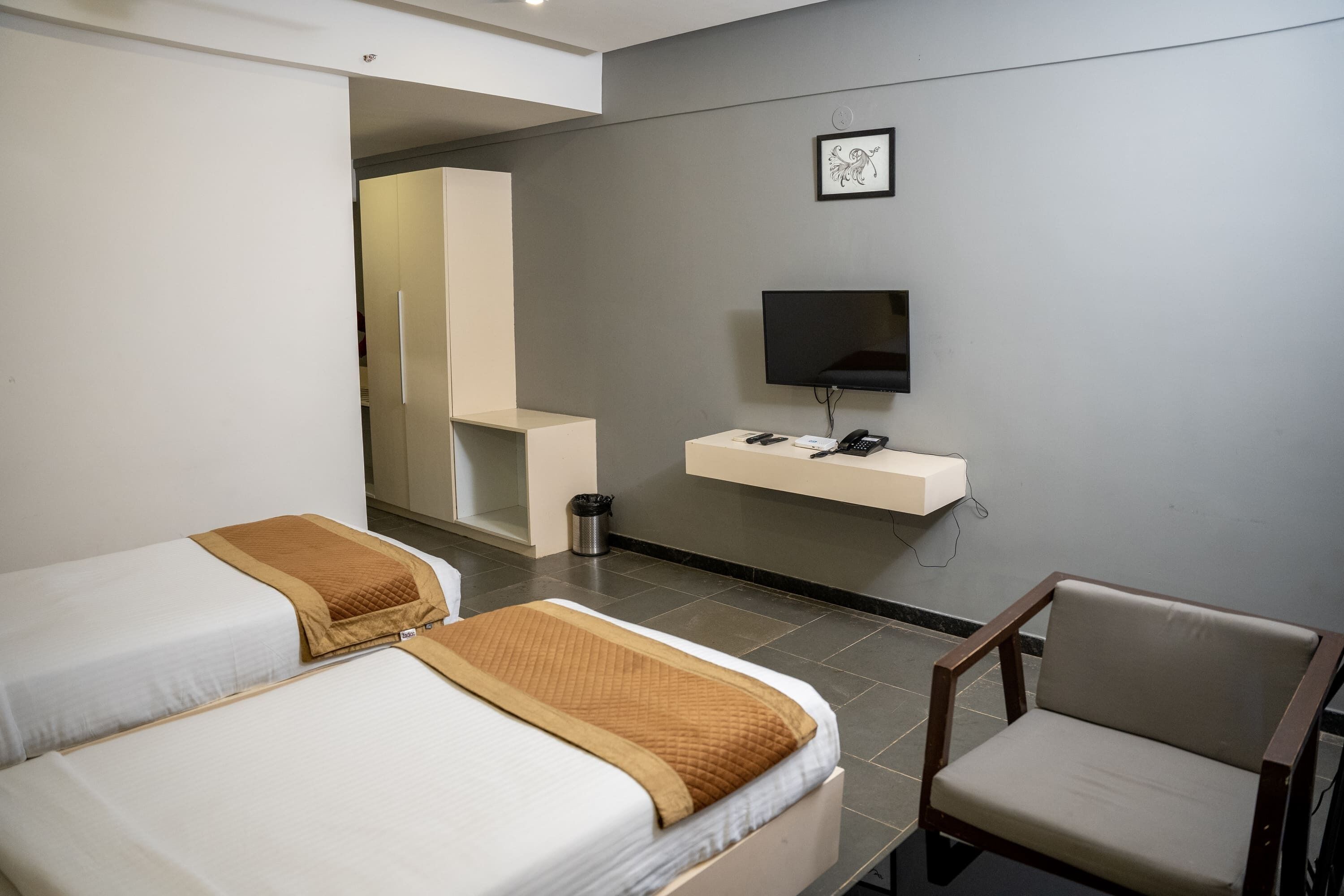 A hotel room with two beds, a TV, a small desk, and a chair.