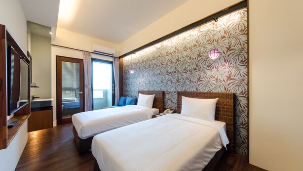 A hotel room with two beds, a bathroom, and a view of the outside.