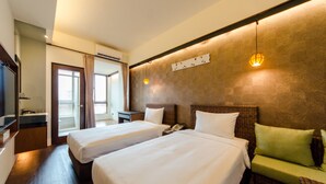 A hotel room with two beds, a small sitting area, a television, and a window with curtains.