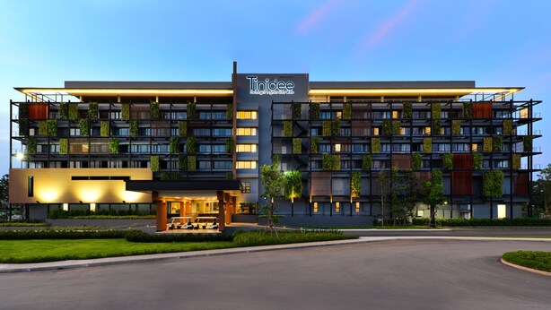 A modern hotel with multiple floors, balconies with greenery, and a well-lit entrance. - Tinidee Hotel Bangkok Golf Club (Pathum Thani)