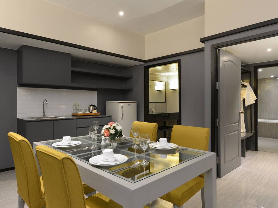 Un comedor moderno con una mesa de vidrio, sillas amarillas y una cocina al fondo.