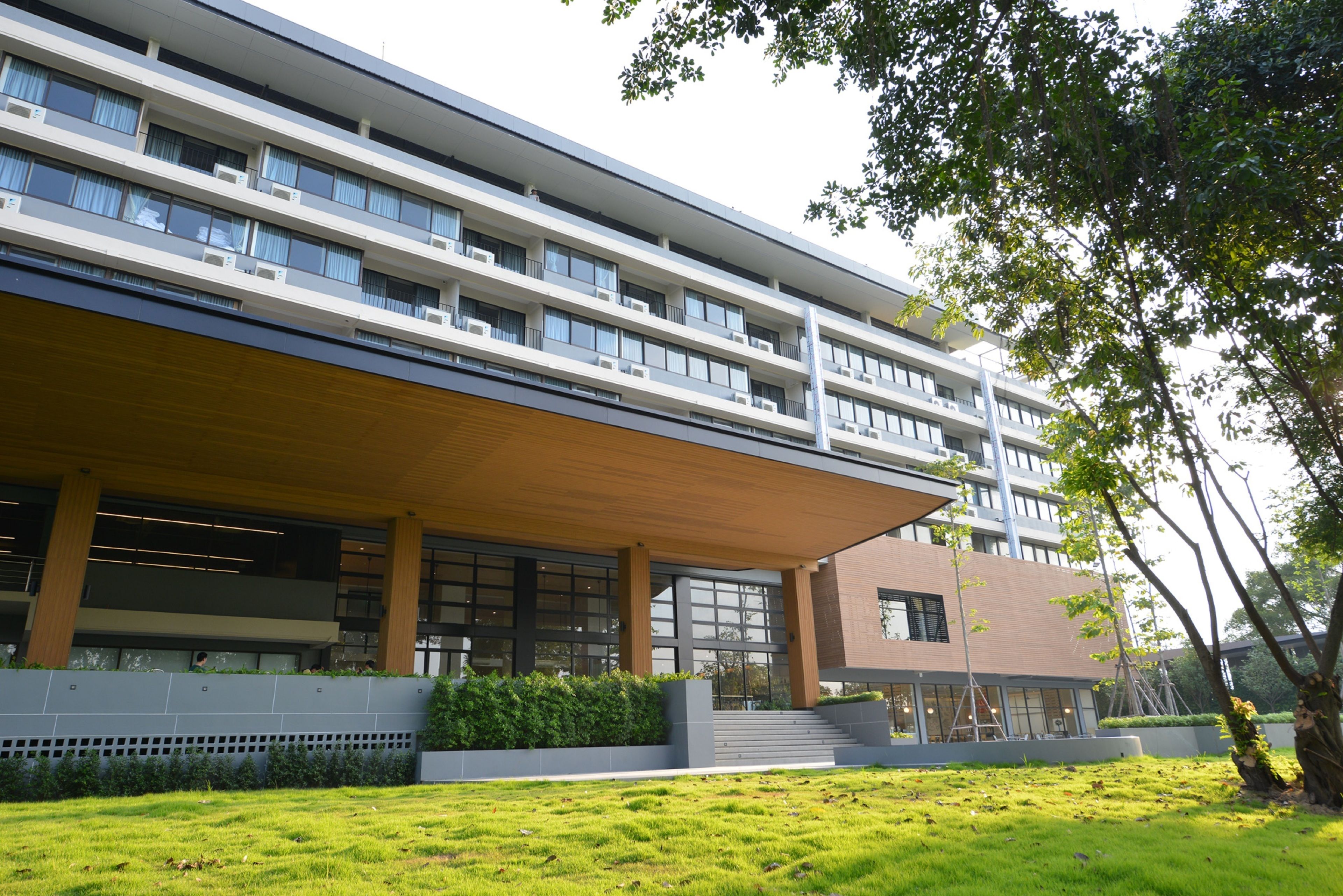 Un edificio moderno de varios pisos, con amplios ventanales y un área de acceso cubierta.