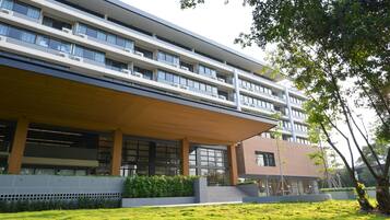 Un edificio moderno de varios pisos, con amplios ventanales y un área de acceso cubierta.