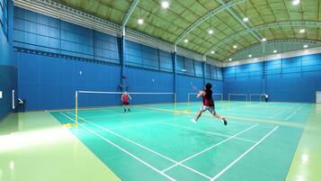 Una cancha de bádminton interior con paredes azules y un techo alto.
