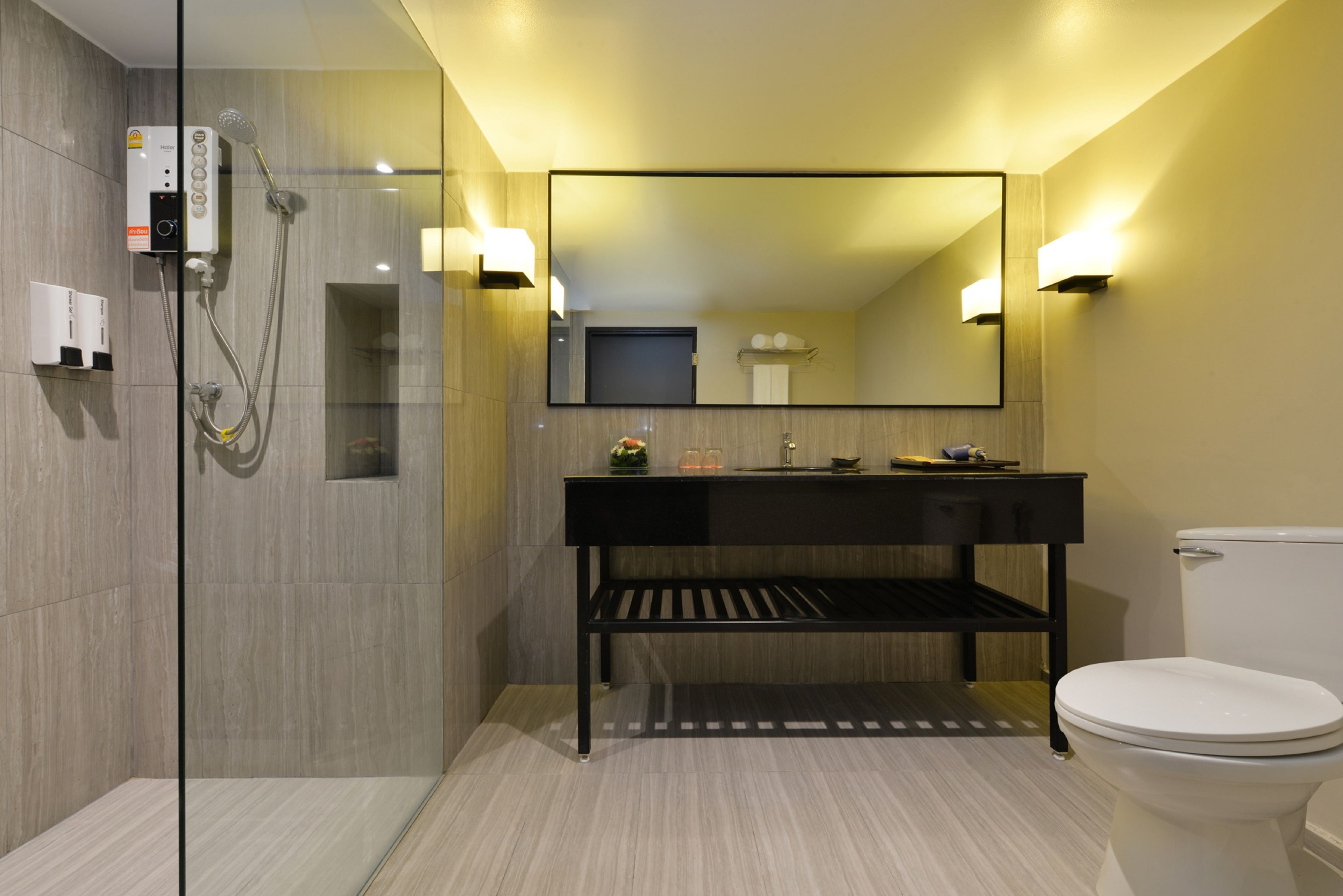 Un bagno moderno con doccia vetrata, un mobile lavabo nero con specchio e un water bianco.