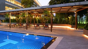 A modern outdoor pool area with a covered seating area and a staircase leading to an upper level. - Tinidee Hotel Bangkok Golf Club (Pathum Thani)