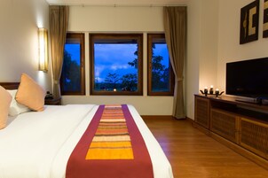 Una habitación de hotel con una cama grande, televisión y vistas al exterior a través de las ventanas.