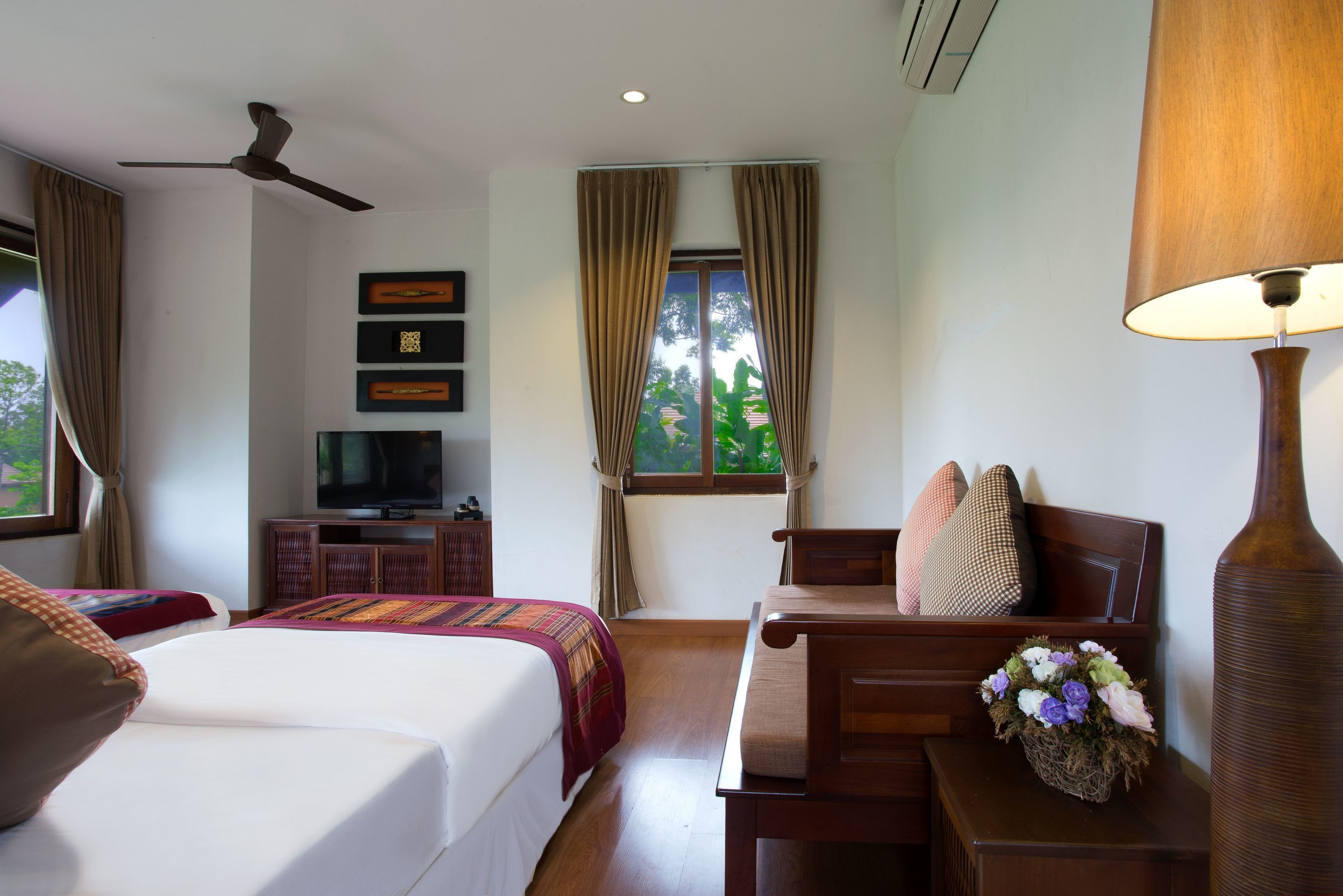 A hotel room with a bed, a desk, a television, and a window with curtains.