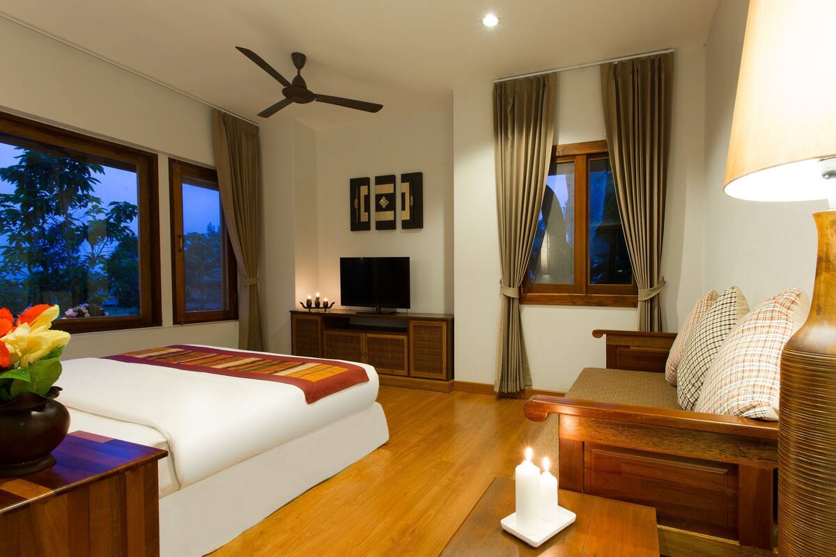 Ein Hotelzimmer mit Bett, Fernseher, Schreibtisch, Lampe und einem Fenster mit Vorhängen.