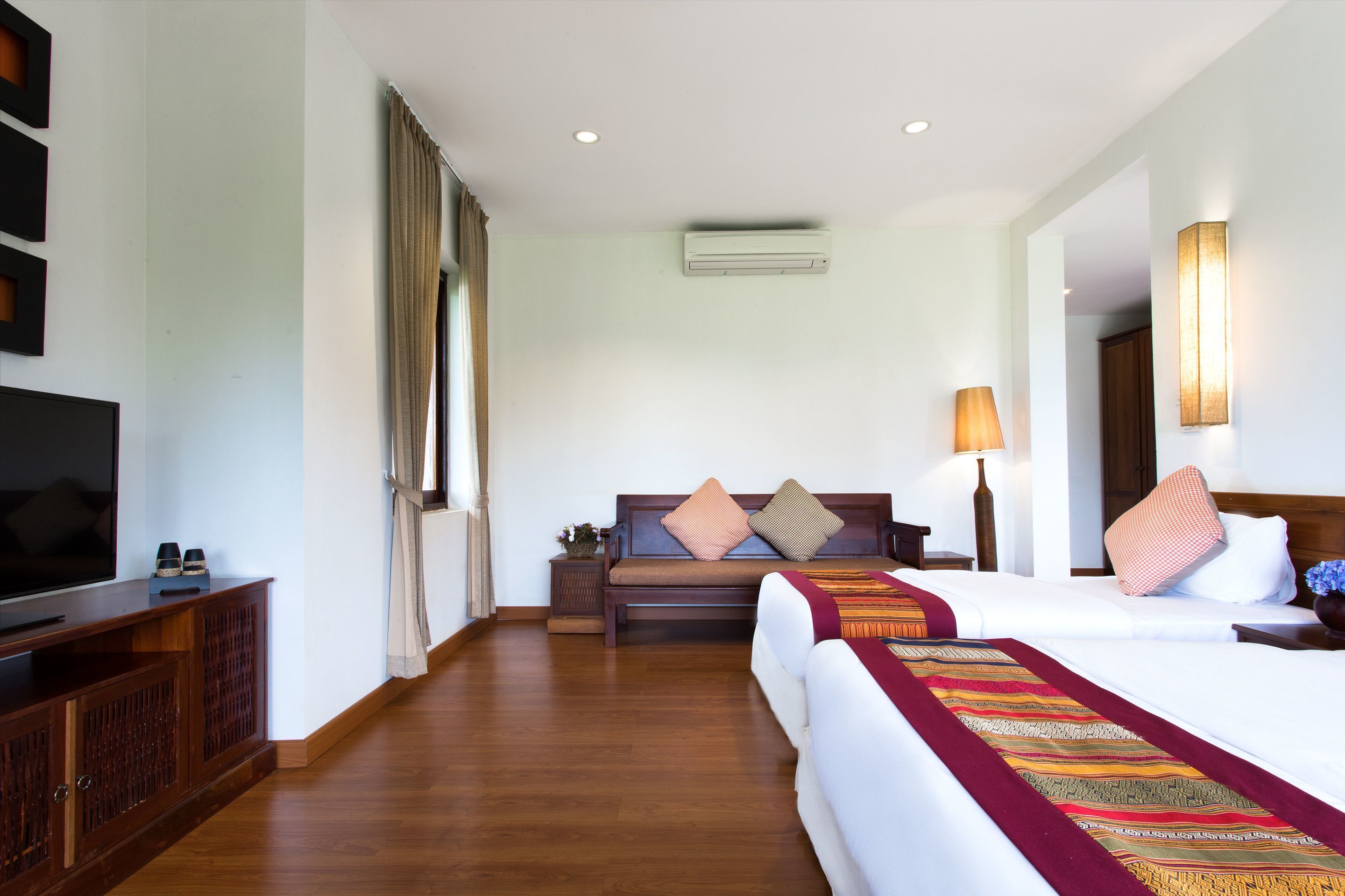 A hotel room with a bed, a sofa, a TV, and a lamp.