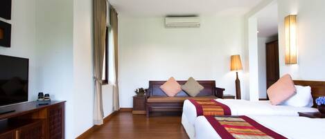 A hotel room with a bed, a sofa, a TV, and a lamp.