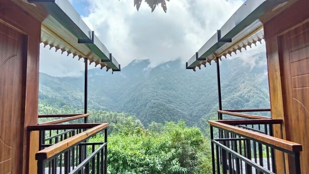 A wooden balcony with a view of a mountainous landscape. - Nature Drops (Kosiyakutoli)