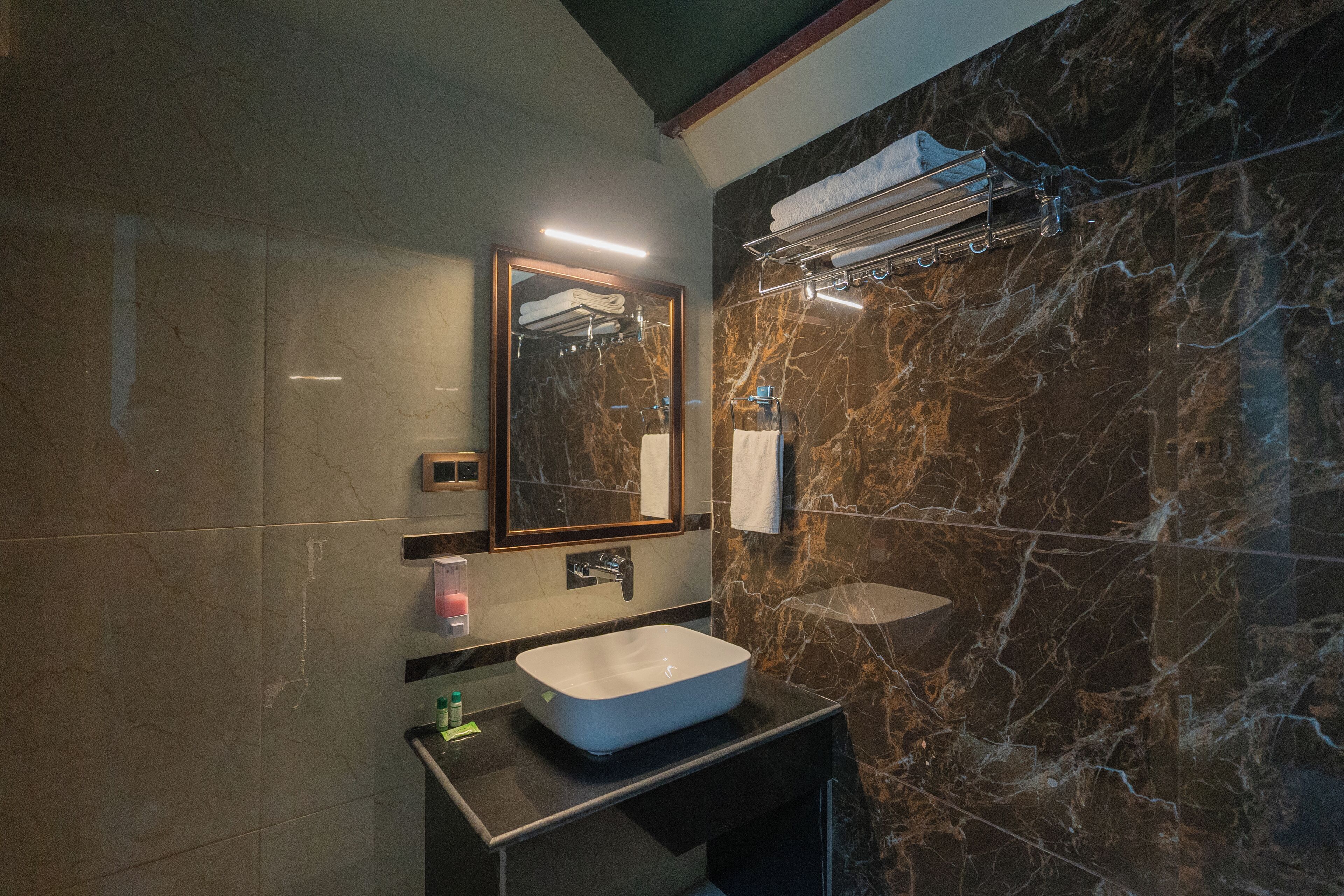 Un baño moderno con lavamanos de mármol, un espejo y un perchero para toallas.