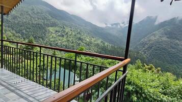 A balcony with a view of a lush valley and mountains.