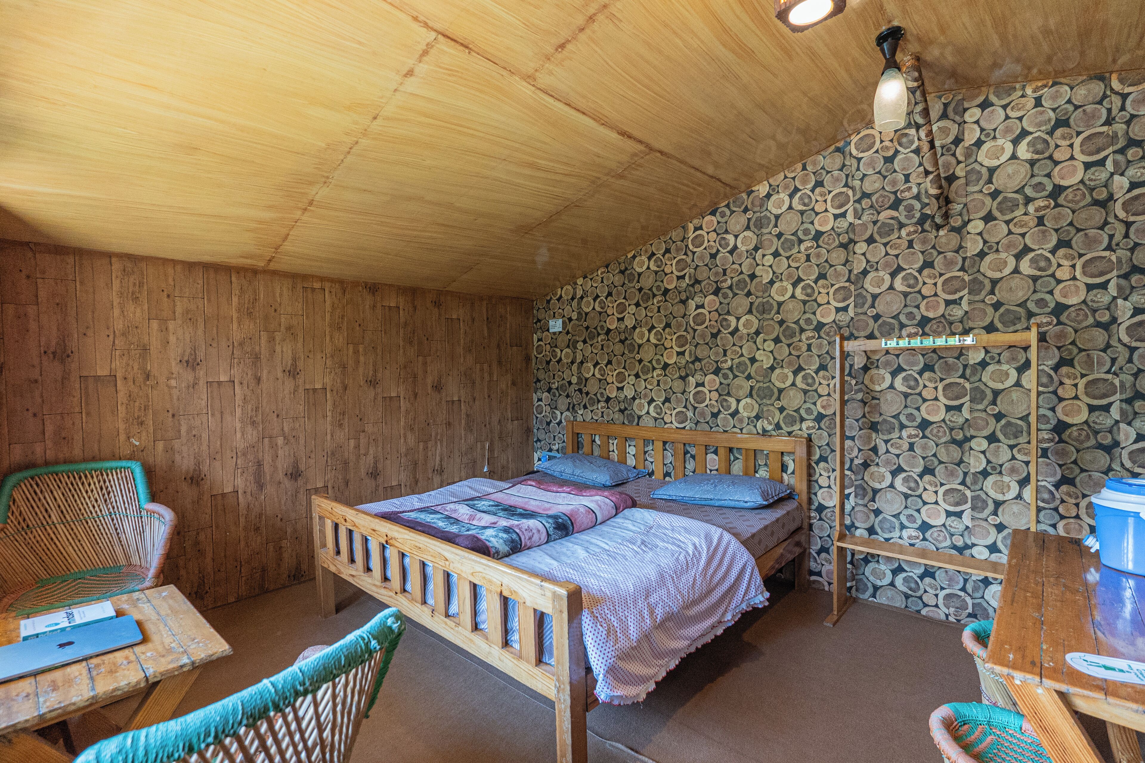 A wooden room with a bed, chairs, and a table.