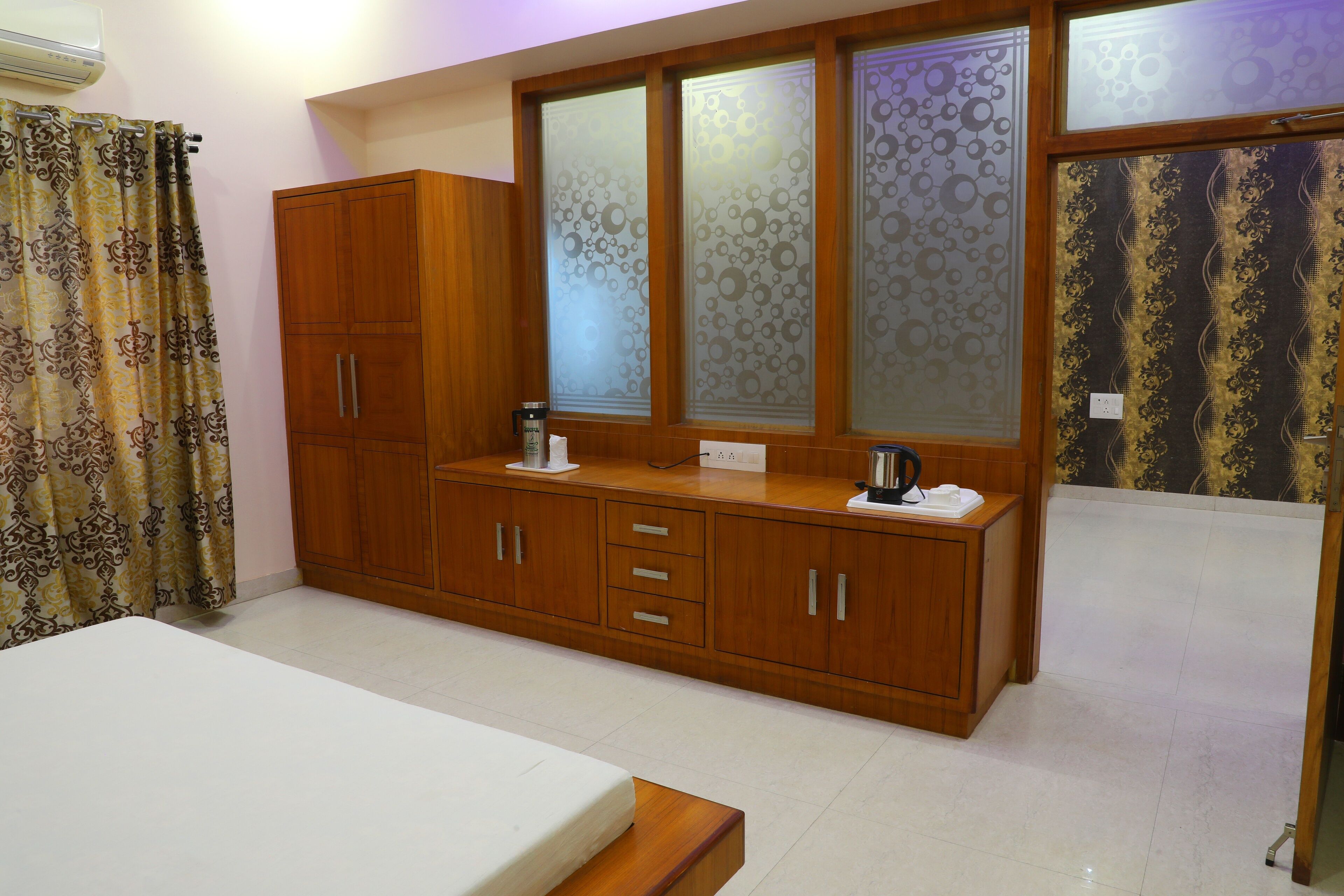 A bedroom with a wooden wardrobe, a bedside table, and a bed.