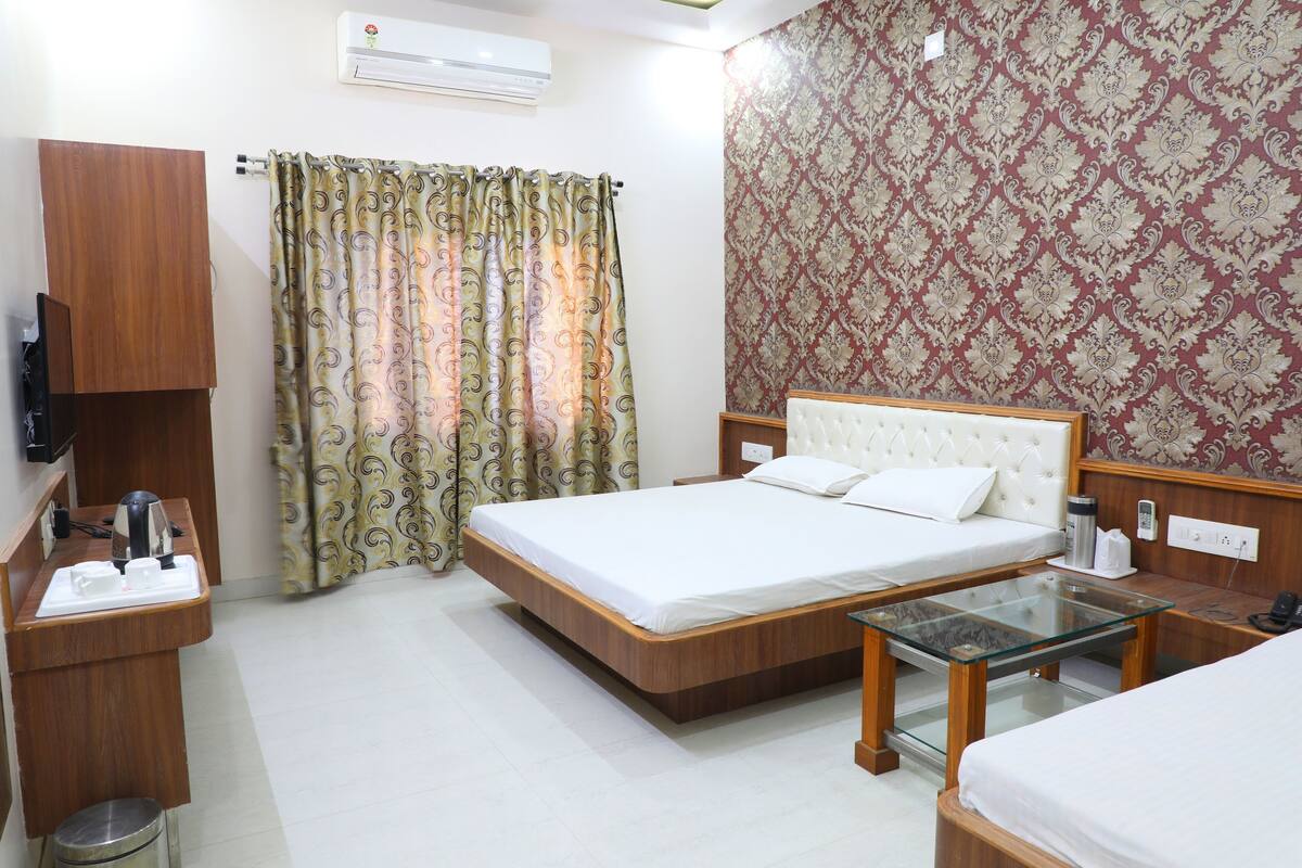 A hotel room with a bed, bedside table, TV, and a patterned wall.