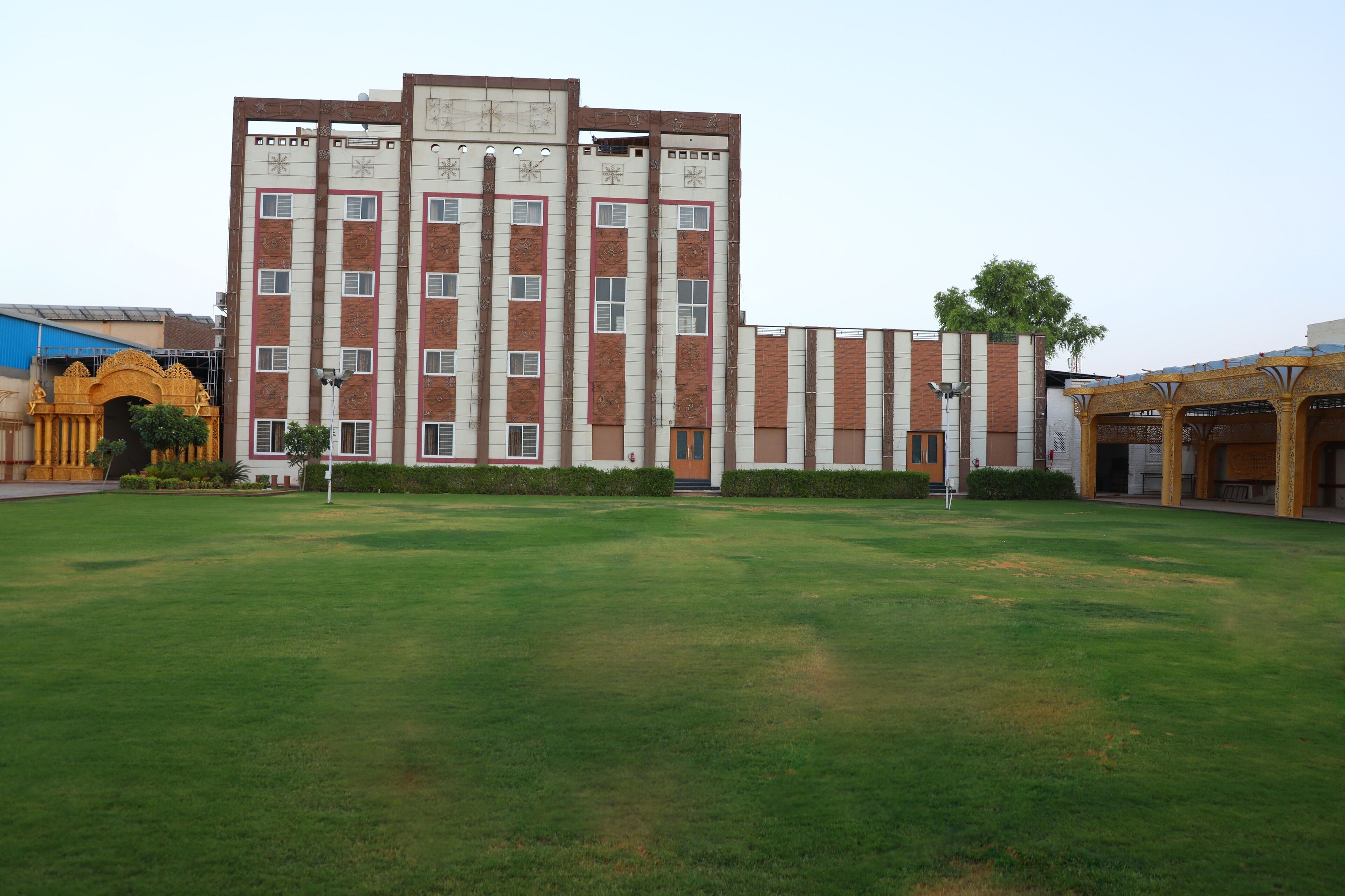 A large building with multiple floors, a central entrance, and a surrounding grassy area.