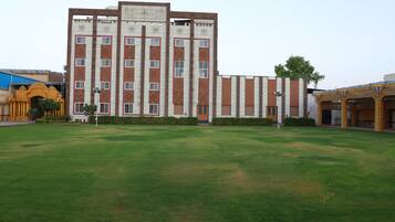 A large building with multiple floors, a central entrance, and a surrounding grassy area.