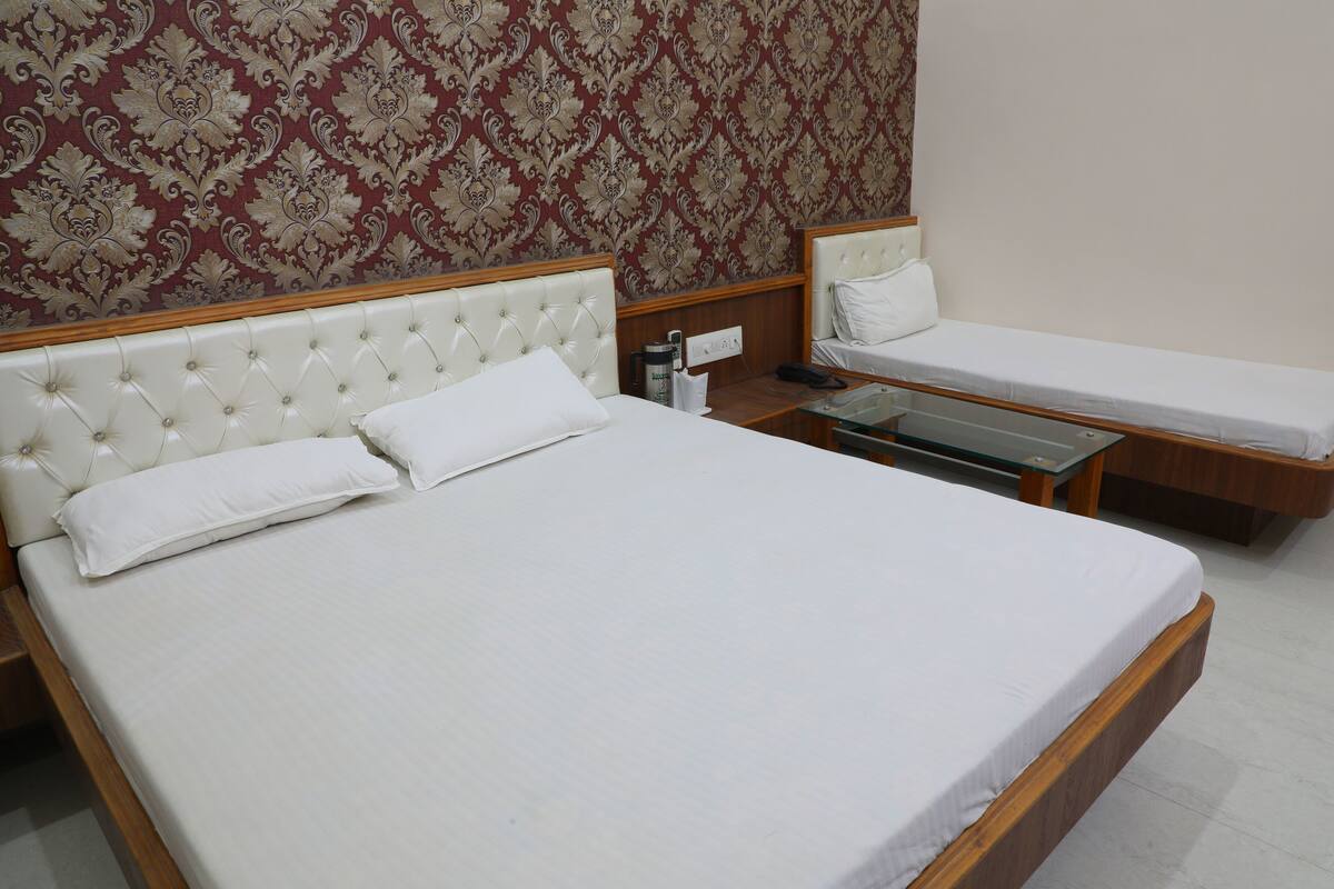 A hotel room with a large bed, a smaller bed, a nightstand, and a mirror.