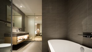 Un baño moderno con una bañera grande, cabina de ducha de vidrio y tocador con espejo.