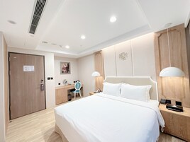 Una habitación de hotel con una cama grande, un escritorio con una silla, un armario y un espejo.