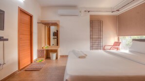 A hotel room with a bed, a chair, a wardrobe, a mirror, and a window. - Kolam Serviced Apartments - Adyar (Chennai)