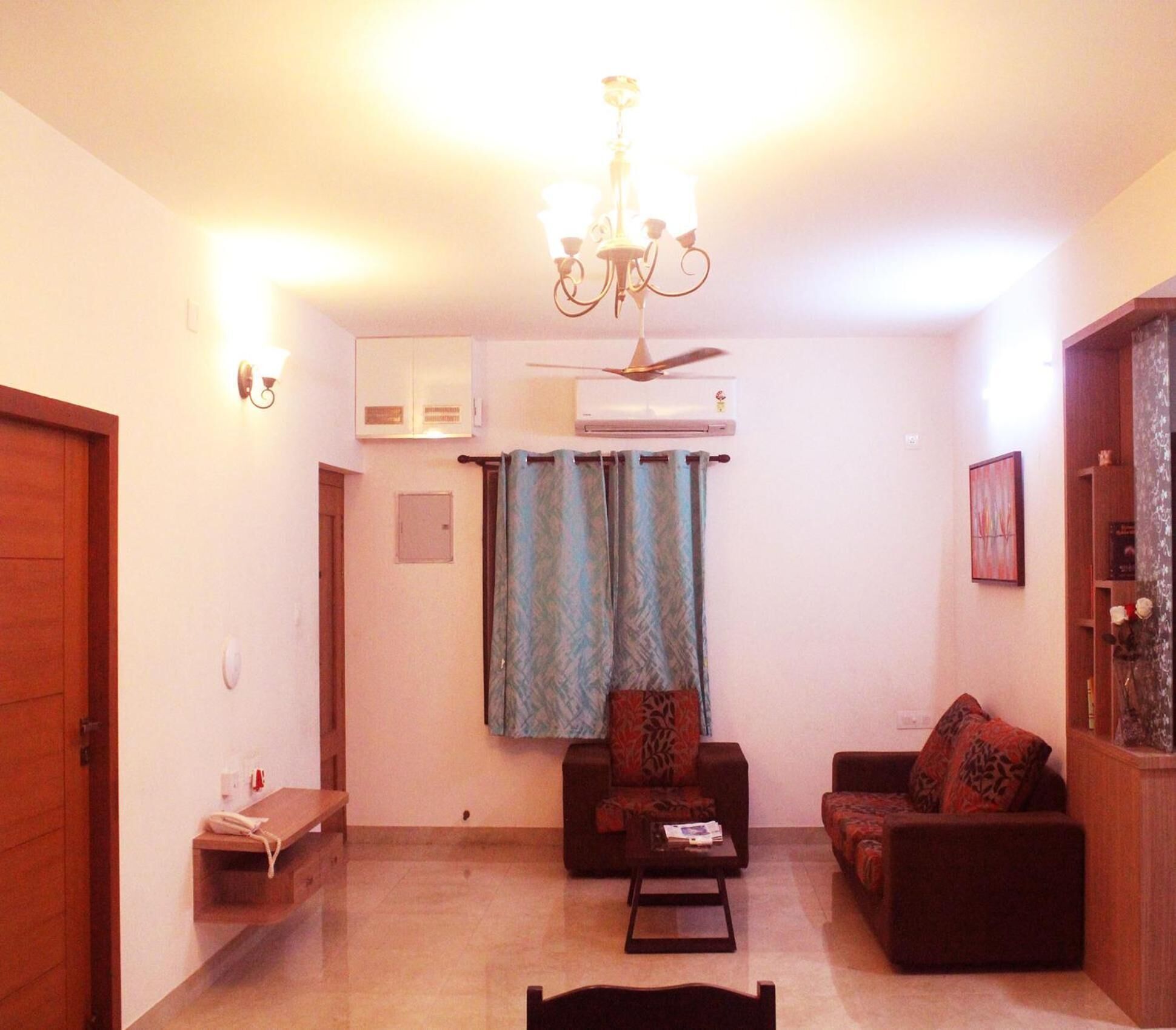 Una sala de estar con candelabro, dos sofás, una mesa de centro y un ventilador de techo.