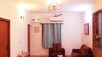 Una sala de estar con candelabro, dos sofás, una mesa de centro y un ventilador de techo.