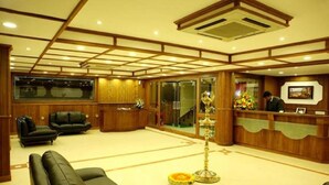 A hotel lobby with a reception desk, seating area, and a staircase. - Aroma Classic Days (Thiruvananthapuram)