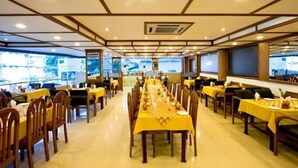 A spacious dining area with multiple tables and chairs, large windows, and a high ceiling with recessed lighting. - Aroma Classic Days (Thiruvananthapuram)
