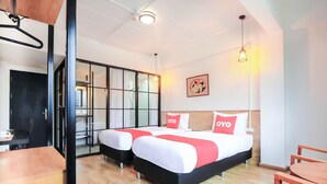 A hotel room with two beds, a dining area, and a sliding glass door leading to a kitchen.