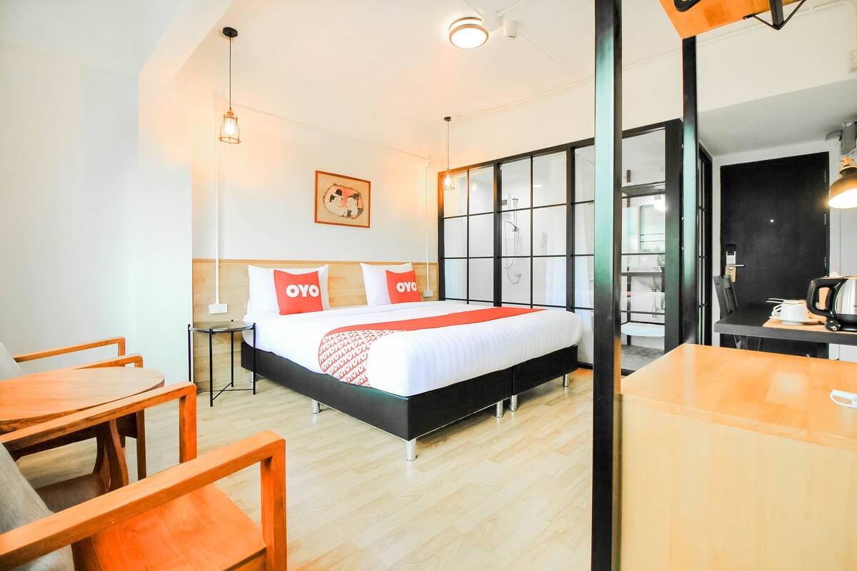 A hotel room with a bed, a wooden table, and a chair.