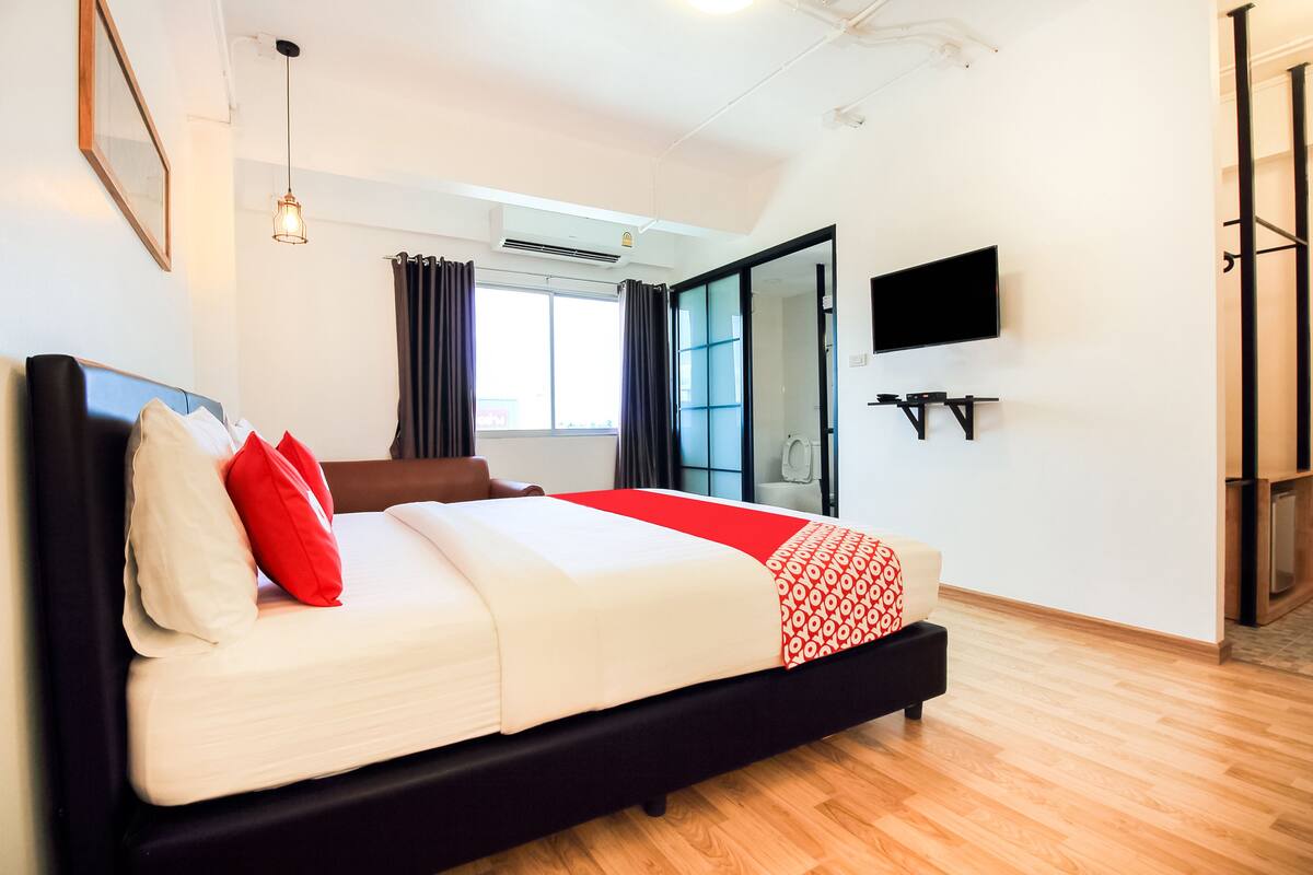 A modern hotel room with a large bed, a flat-screen TV, and a sliding glass door to the balcony.