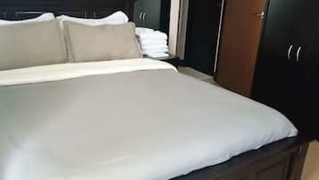 A bedroom with a large bed, a wardrobe, and a mirror.
